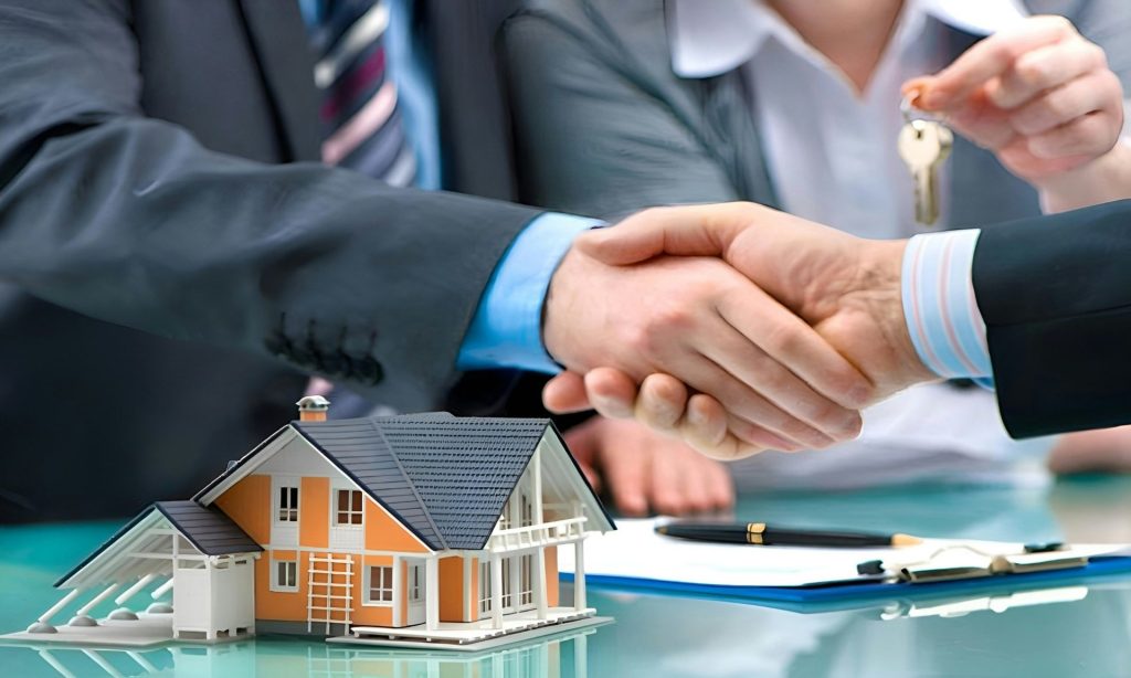 Two men shaking hands over a house model and keys