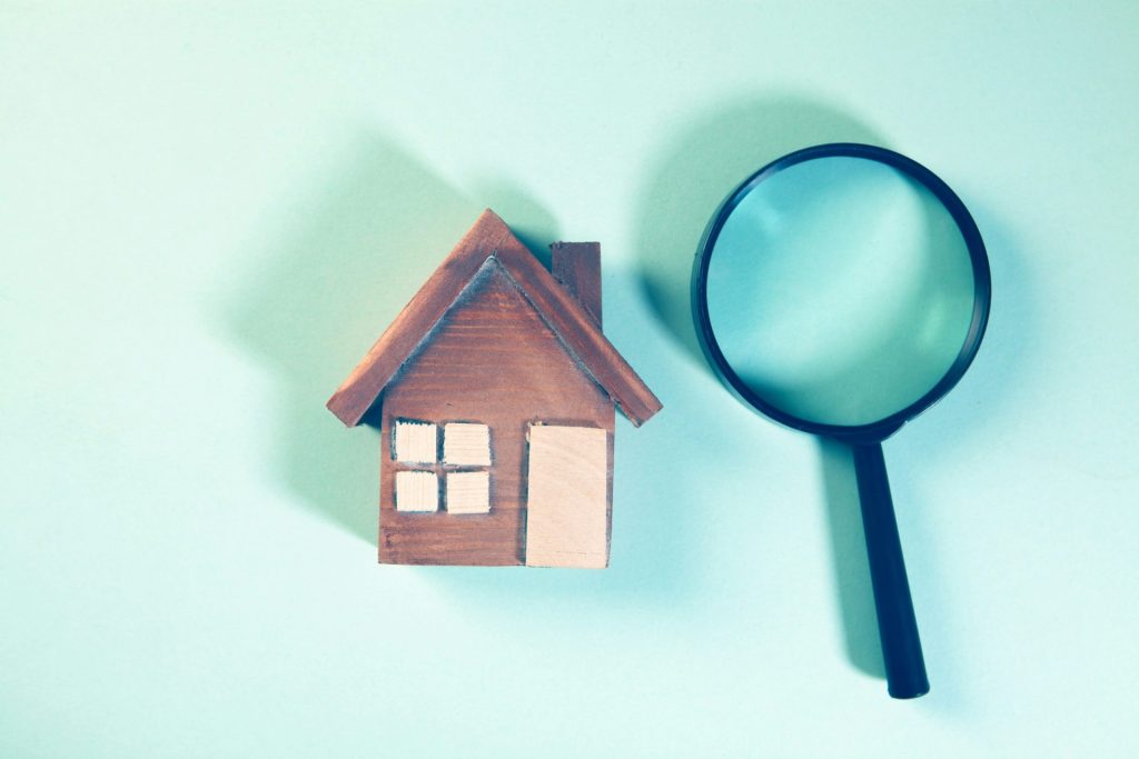 Magnifying glass over a wooden house model