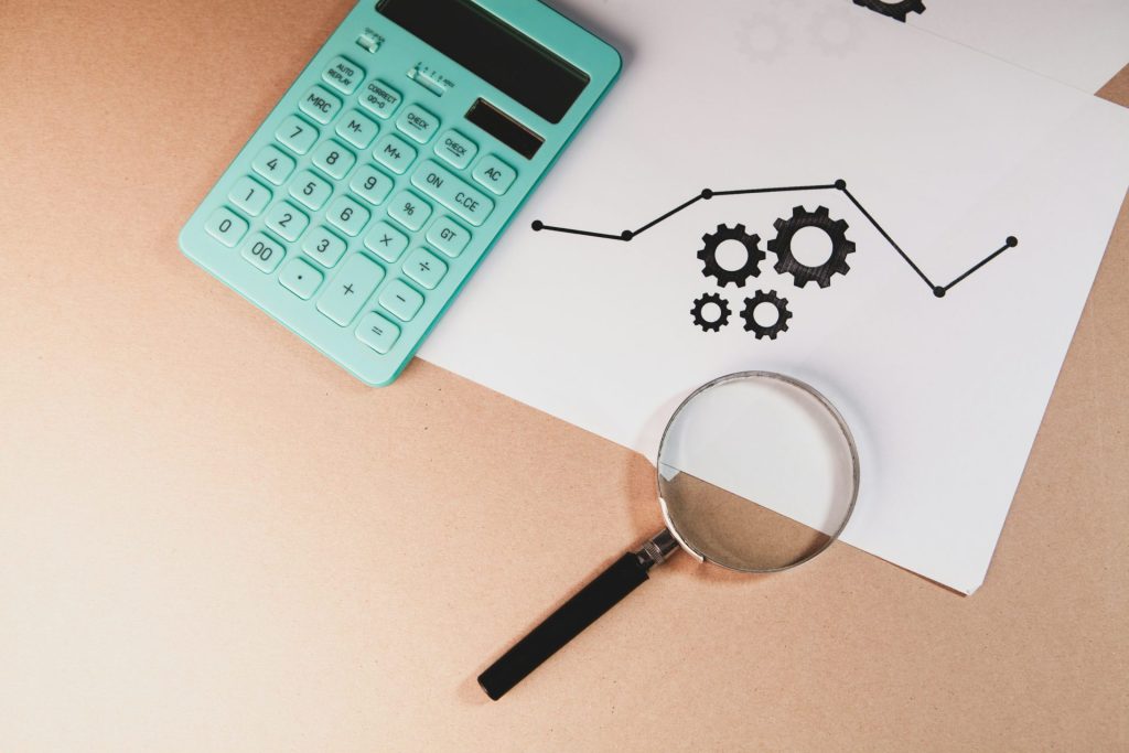Calculator, magnifying glass, and chart with gears on paper